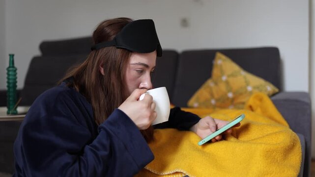 Coffee and social media create an instant dopamine routine as a young woman scrolls on her phone after waking instead of giving her mind a calm and healthy start each day