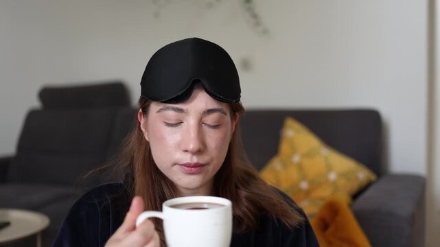 Coffee gives her a quiet moment to wake up as a sleepy young woman slowly enjoys the first warm sip before the day begins and the routine takes over