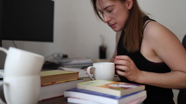 Study continues after the last sip as a determined young woman sets down an empty coffee mug and returns to her books relying on caffeine to stay productive