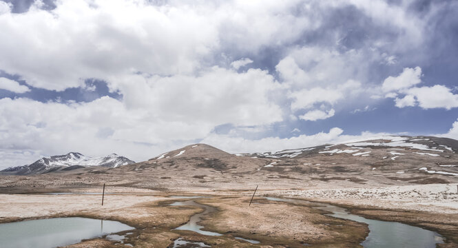 Clear-water rivers and lakes in a mountain valley, pastures and green grassy fields set against mountain ranges and snow-capped, glacier-clad peaks&mdash;a scenic landscape background