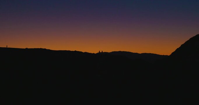 Silhouetted People Walking Along Ridge at Zabriskie Point Sunset, Death Valley