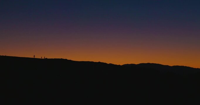 Silhouetted People Walking Along Ridge at Zabriskie Point Sunset, Death Valley
