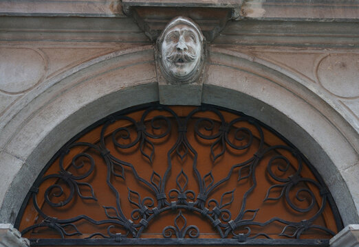 Head of man with mustache, arch keystone, decorative architectural, openwork metal grille. Koper, Slovenia.