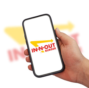 In-N-Out Burger logo displayed on smartphone screen held by hand illustrative editorial
