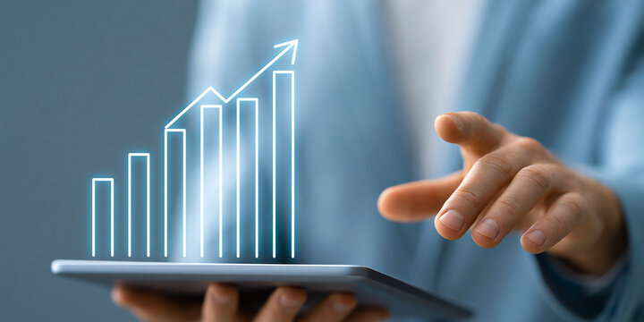 Support desk agent gesturing toward a projected growth chart with a glowing blue chart icon on stage, perfect for modern lifestyle and business storytelling, with a naturally evocative visual mood.