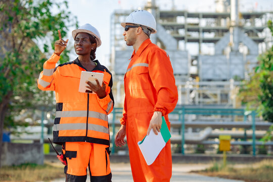 Maintenance specialists inspecting industrial facility while reviewing engineering documents digital checklist. Operational efficiency, preventive maintenance, industrial teamwork plant reliability.