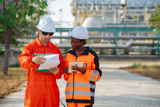 Industrial engineer explaining inspection findings to maintenance colleague during field assessment at processing plant. Technical communication, engineering operations, equipment monitoring