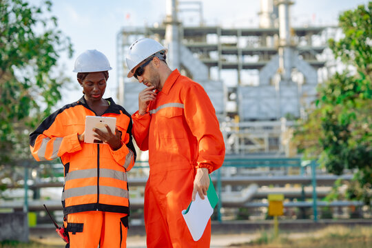 Engineering professionals performing site inspection with digital tablet and maintenance records at industrial plant. Equipment assessment, engineering support, safety procedures technical operations.