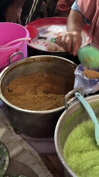 Person stirring traditional sweet porridge in a large pot at a street market.