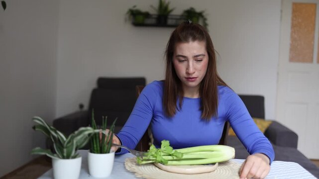Trying to ignore hunger young woman quietly convinces herself that celery is enough while obsessive calorie counting turns every meal into emotional struggle daily