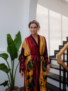 Elegant woman wearing luxury kimono robe in modern tropical home