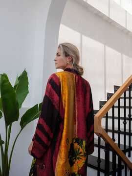 Elegant woman wearing luxury kimono robe in modern tropical home