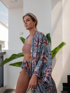 Elegant woman wearing luxury kimono robe over  swimsuit in modern tropical villa