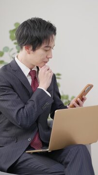 仕事中にスマホを見るビジネスマン男性