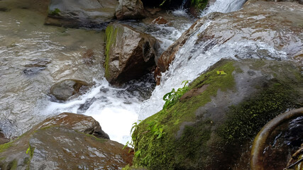 Flowing river waterfall cascading over wet mossy rocks in nature © Fikri Fachry