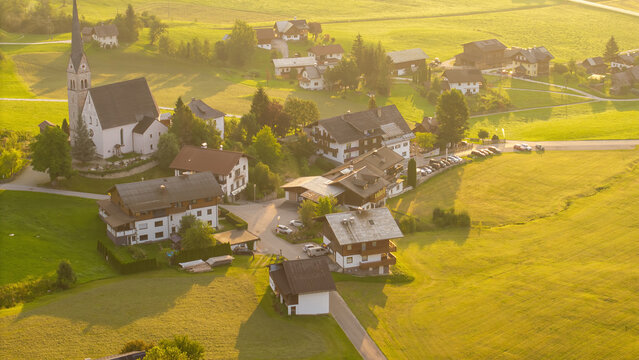 Alpine green fields, church and traditional wooden houses view of the Gosau village at summer sunny morning.