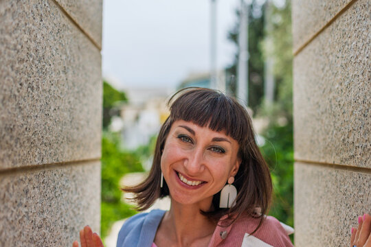 Smiles, is happy and laughs: a fashionable woman in a city style, with fashionable and simple clothes. A portrait of a woman in urban clothing.