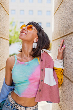 A portrait of a beautiful young woman outdoors. She is wearing colorful clothing and is smiling and laughing.