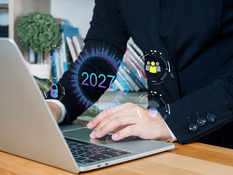 Laptop computer business person typing with digital interface showing 2027 office workspace technology concept future year online security data protection communication innovation finance