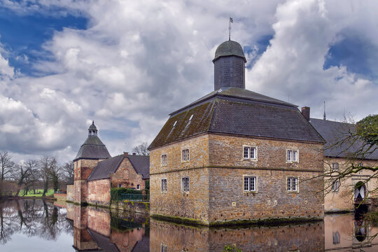 Westerwinkel Castle in Germany close view across water. Early baroque square fortress building moat under daytime sky