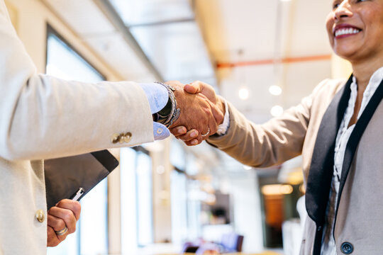 Two business colleagues shaking hands as a sign of business deal, collaboration, and agreement in a modern coworking space