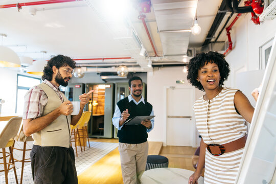 Diverse team of professionals standing in modern coworking office, brainstorming ideas and collaborating on new business projects