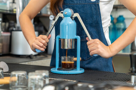 Small business entrepreneur coffee shop cafe restaurant. Asian woman barista using manual espresso maker making freshly brewed coffee on bar counter. Waitress serving beverage drink to customer.