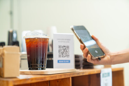 Cashless qr code payment by smartphone at coffee shop, customer scanning mobile payment electronic banking while cafe owner serving takeaway coffee, digital transaction and small business technology