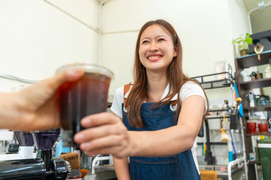 Female barista serving fresh iced coffee to customer at cafe counter, professional beverage drink preparation specialty coffee and tea shop, small business hospitality and takeaway drink service