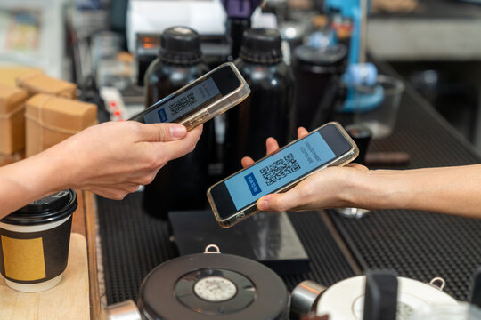 Cashless qr code payment by smartphone at coffee shop, customer scanning mobile payment electronic banking while cafe owner serving takeaway coffee, digital transaction and small business technology