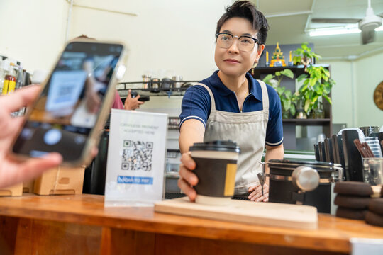 Cashless qr code payment by smartphone at coffee shop, customer scanning mobile payment electronic banking while cafe owner serving takeaway coffee, digital transaction and small business technology