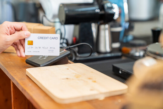 Credit card payment at coffee shop counter. Cafe owner using card reader for cashless transaction while serving coffee drink to customer. Electronic payment technology for small business retail store.