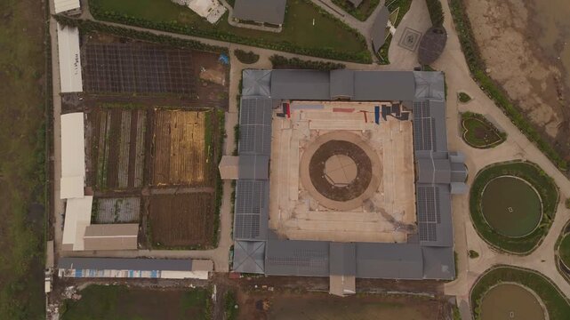 Aerial top view of modern institutional building with rooftop solar panels and surrounding agricultural fields in Surat India