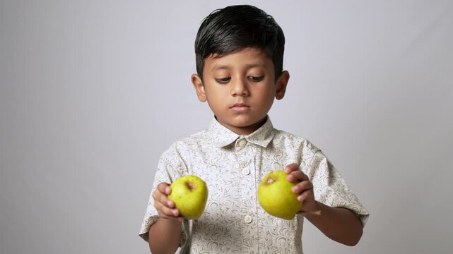 Indian boy holding fresh green apples. Child choosing healthy organic fruit for nutrition.