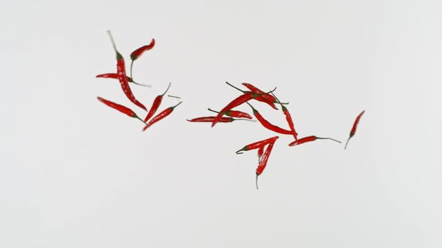 Super Slow Motion Shot of Flying Red Chilli Peppers Isolated on White Background at 1000fps.