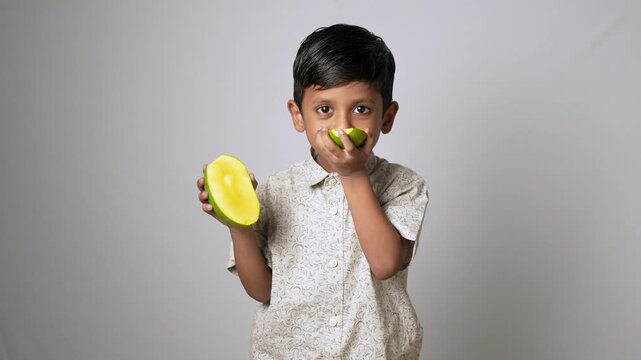 Indian boy holding fresh mango slices. Healthy child eating organic tropical fruit.