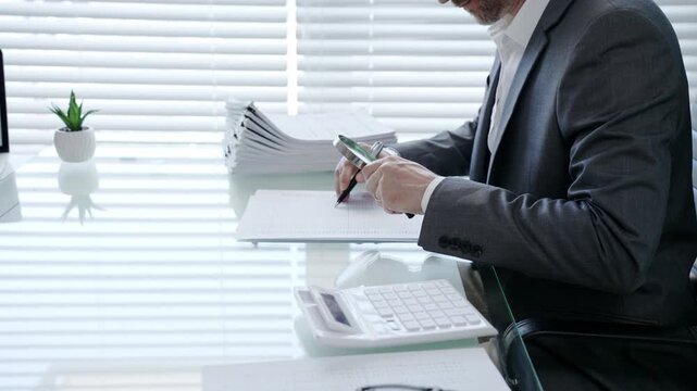 Businessman using a magnifying glass to meticulously examine a financial document at a modern office desk, scrutinizing details for accuracy and compliance in auditing processes