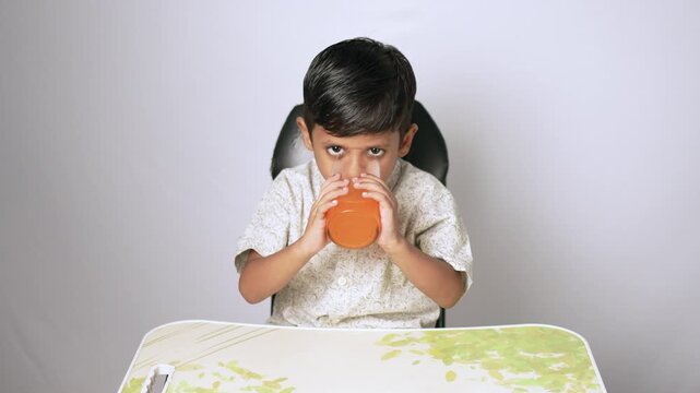 Indian boy drinking juice. Child enjoying a healthy fruit beverage at home.