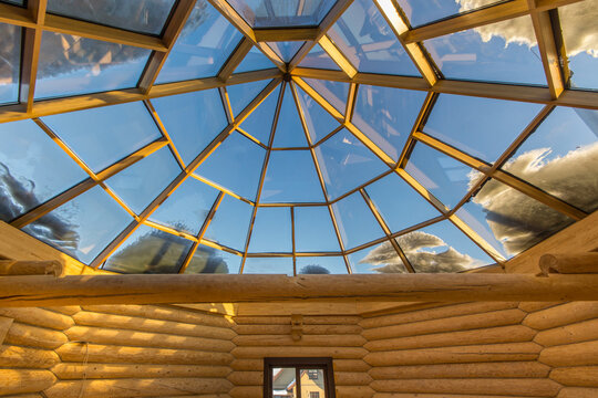 Magnificent design of the attic of a wooden house made of solid logs. Domed glass roof. Unfurnished.