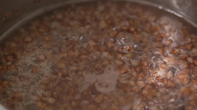 Close-up view of brown buckwheat groats boiling in hot water.