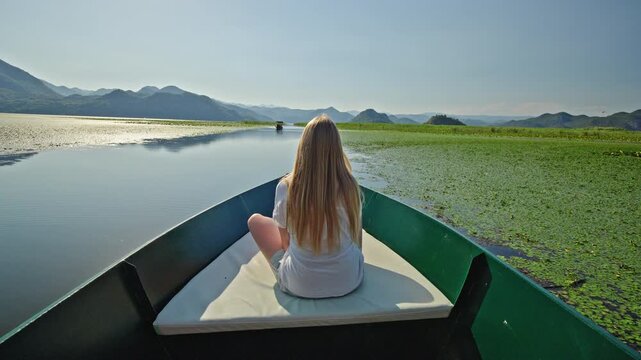 Teenage girl enjoying a boat trip across Skadar Lake National Park in Montenegro. Scenic summer panorama of tranquil freshwater
