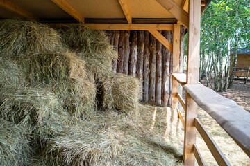 Rustic barn stall with stacked hay bales and straw bedding © Alexander