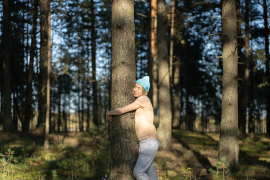 Loving nature purity. Relaxed woman hugging tree trunk in autumn forest at sunset. Happy calm female recreating in woods outside city on weekend spend day, enjoying silence in woodland. Stress relief