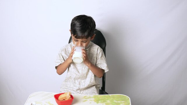 Indian boy drinking milk. Child eating healthy breakfast at home.