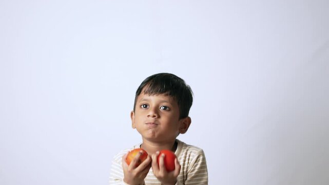Indian boy holding fresh tomatoes. Child learning about healthy organic food and nutrition.