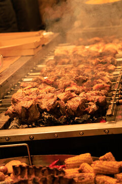 Grilling meat on skewers at a busy street market during the evening hours