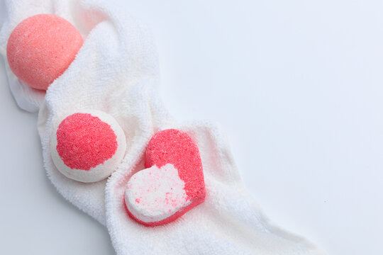 Pink bath bombs arranged on a white towel showing a heart shape and round shapes in a well lit setting