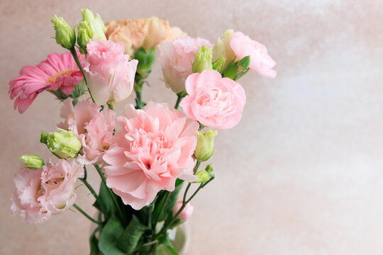 Fresh cut flowers in a clear vase on a plain background during daylight