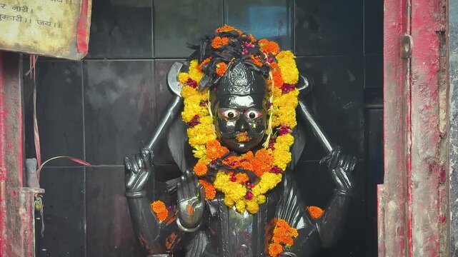 Beautiful idol of Lord Shani Dev decorated with fresh flower garlands inside a temple shrine. The deity symbolizes justice, karma, discipline, and divine protection