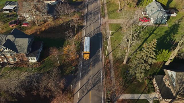 Aerial view of yellow American school bus driving through a suburban neighborhood in the United States